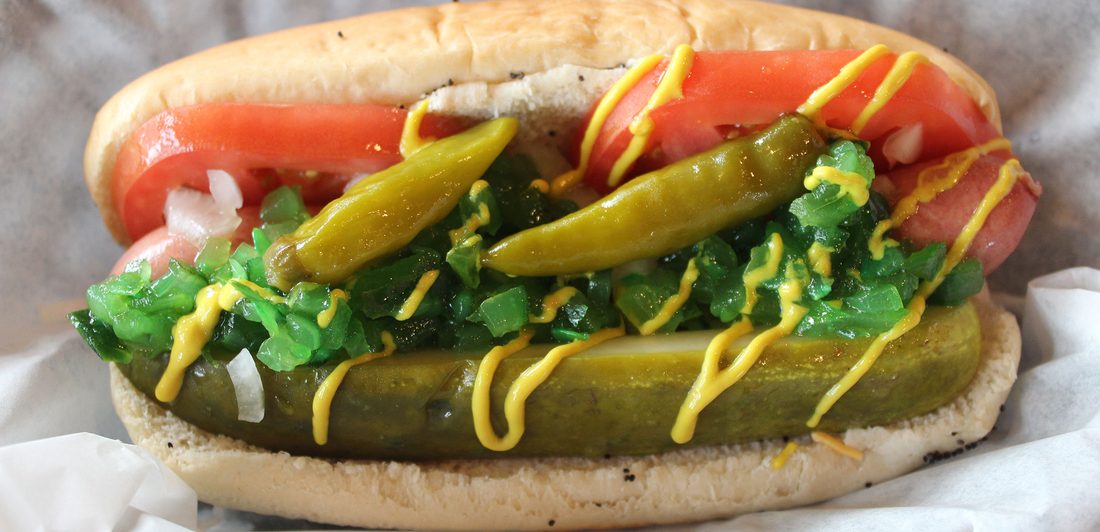 Chicago-style hot dog with mustard, relish, sport peppers, tomato and a pickle spear
